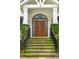 Elegant front entrance with a decorative wooden door, accented by lush greenery and brick steps at 104 Beach St, Mount Pleasant, SC 29464