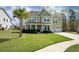 Charming two-story home features a manicured lawn, attached two-car garage, and a beautiful palm tree in the front yard at 136 Stagecoach Ln, Summerville, SC 29483