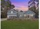 Charming blue home with a red door, black fence, and a well-manicured lawn under a lovely sunset at 1543 Scott Hill Rd, James Island, SC 29412