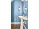 Stylish powder room with a modern pedestal sink, unique mirror, and chic blue wall at 1813 Parkland Preserve Ln, Charleston, SC 29412
