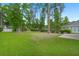A spacious, grassy backyard is bordered by a wrought iron fence and mature trees at 207 Brutus Ln, Summerville, SC 29485