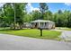 Inviting single-story home with a covered porch, gravel driveway, and lush green lawn at 208 General Moultrie Dr, Bonneau, SC 29431