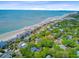 Aerial view showcasing coastal homes, lush greenery, and the ocean, perfect for serene living at 22 Beachwood East, Isle of Palms, SC 29451