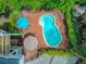 An aerial view shows a kidney-shaped pool with brick patio and seating as well as the lush greenery around the property at 22 Beachwood East, Isle of Palms, SC 29451