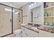 Neutral toned bathroom showcasing a glass door shower, marble countertops, and decorative shelving at 22 Beachwood East, Isle of Palms, SC 29451