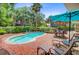 A kidney-shaped pool is surrounded by a brick patio with lounge chairs and a table, and mature landscaping at 22 Beachwood East, Isle of Palms, SC 29451