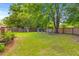 Large grassy backyard with mature trees, a wooden fence, and chairs create a relaxing outdoor space at 230 Azalea Ct, Moncks Corner, SC 29461