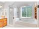 Bright bathroom with a large window, bathtub, separate shower, and wood cabinets at 310 Christiee Ct, North Charleston, SC 29418
