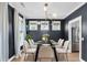 Elegant dining room with dark walls, a glass table, modern chandelier and bright, airy windows at 327 Megans Bay Ln, Charleston, SC 29492