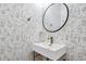 Stylish powder room featuring unique wallpaper, modern sink with gold fixtures, and sleek oval mirror at 327 Megans Bay Ln, Charleston, SC 29492