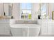 Elegant bathroom featuring a modern soaking tub, dual vanities, and a view to the outside at 3285 Johnstowne St, Johns Island, SC 29455