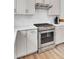Close-up of a stainless steel oven with a gas cooktop set into white quartz countertops and white subway tile backsplash at 350 Dahlia Row Dr, Summerville, SC 29486
