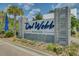 Del Webb Nexton community sign surrounded by palm trees, plants, and flowers near the entrance at 350 Dahlia Row Dr, Summerville, SC 29486