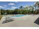 Community pool area surrounded by lounge chairs and lush trees on a sunny day at 415 W Respite Ln, Summerville, SC 29483