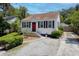 Charming home with a red door, black shutters, well-maintained landscaping, and a gravel driveway at 4932 N Rhett Ave, North Charleston, SC 29405