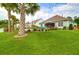 The backyard boasts a covered patio, lush lawn, tropical palms, and inviting pool area at 5509 Alpine Dr, Summerville, SC 29483