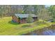 Charming log cabin home with a green metal roof, screened porch, and surrounded by a lush lawn and pond at 5519 Jefferies Hwy, Walterboro, SC 29488