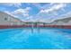 A clear, blue swimming pool surrounded by a wooden fence and several houses under a cloudy blue sky at 575 Rosings Dr, Summerville, SC 29486