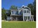 Charming two-story home with stone accents, black shutters, attached garage, and lush green lawn at 6121 Sourwood Trl, Ridgeville, SC 29472