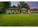 Charming white brick home with a well-manicured lawn, rocking chairs, and lovely landscaping at dusk at 114 Bailey Dr, Summerville, SC 29485