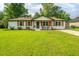 Charming white brick home with a well-manicured lawn, rocking chairs, and lovely landscaping at 114 Bailey Dr, Summerville, SC 29485