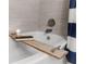 Bright bathroom features a shower and tub combination, and a wooden shelf above tub at 1145 Bellwood Rd, Charleston, SC 29412