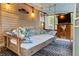 Cozy screened porch with a hanging daybed, pillows, and a TV on a wicker stand, perfect for relaxation at 1145 Bellwood Rd, Charleston, SC 29412