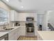 Bright kitchen featuring stainless steel appliances, white cabinets, and a view of the stairway at 117 Macy Cir, Goose Creek, SC 29445