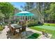 A beautiful backyard with a green outdoor turf, a grill, chairs, a table, and an umbrella at 1227 Ocean View Rd, Charleston, SC 29412