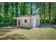 A well-maintained white shed with a garage door surrounded by trees in the backyard at 123 Azalea Dr, Summerville, SC 29485