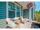 Cozy front porch with cushioned wooden chairs, end table, and hanging plants on a sunny day at 1589 Seabago Dr, Charleston, SC 29414