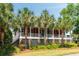 Inviting two-story home with a charming front porch and beautiful palm trees enhancing the curb appeal at 16 Fairway Village Ln, Isle of Palms, SC 29451