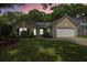 Charming one-story home with a two-car garage, well-manicured lawn, and mature trees at sunset at 1939 Oak Tree Ln, Mount Pleasant, SC 29464