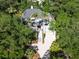 An aerial view of a home surrounded by trees shows its driveway, multiple stories, and charming design elements at 24 Beachwood West, Isle of Palms, SC 29451