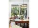 Dining area with a wood table, chairs and light fixture, with a view of a porch and wooded area at 24 Beachwood West, Isle of Palms, SC 29451