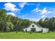Spacious backyard featuring a modern white home, a large lawn, and mature trees under a blue sky at 2470 Breakaway Trl, Johns Island, SC 29455