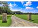 Picturesque view of property with white farmhouse and barn at the end of a long driveway lined with brick columns at 2470 Breakaway Trl, Johns Island, SC 29455