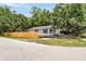 Charming single-story home featuring light gray siding, black shutters, a cozy front porch, and a wooden fence at 2678 Ranger Dr, North Charleston, SC 29405