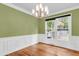 Elegant dining area featuring hardwood floors, a modern chandelier, wainscoting and large windows at 320 Compton Xing, Summerville, SC 29485