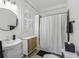 Well-lit bathroom with a pedestal sink, round mirror, and shower-tub combination at 33 Pitt St # 3, Charleston, SC 29401