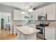 White kitchen features an island, stainless steel appliances, bright lighting, and decorative tile backsplash at 334 Mossy Oak Way, Mount Pleasant, SC 29464