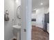 Stylish half bath with pedestal sink and oval mirror plus wood-look floors into the adjacent modern kitchen at 411 Bering Ln, Summerville, SC 29486