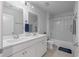 Bright bathroom featuring double sink vanity, framed mirrors, and a shower-tub with white tile at 411 Bering Ln, Summerville, SC 29486