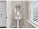 Stylish powder room with pedestal sink, oval mirror, and natural light at 5138 Preserve Blvd, Ladson, SC 29456