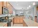 Well-lit kitchen boasts wooden cabinets, granite countertops and stainless steel appliances, open to the living room at 5433 Falling Tide, North Charleston, SC 29420