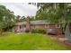 A spacious backyard with a brick house, lawn, patio, and mature trees providing shade at 614 Beauregard St, Charleston, SC 29412