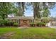 Charming brick home featuring a well-manicured lawn and lush landscaping with mature trees and Spanish moss at 614 Beauregard St, Charleston, SC 29412