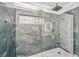Modern walk-in shower featuring glass door, gray tiled walls, stone floors and a built-in bench at 69 King Charles Cir, Summerville, SC 29485