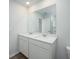 Bathroom features a dual sink vanity with modern fixtures, a large mirror, wood look floors and white cabinets at 737 Meadowbrook Ln, Summerville, SC 29486