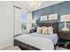 Modern bedroom featuring a large wooden bed frame, stylish lighting, and a calming blue accent wall at 760 Meadowbrook Ln, Summerville, SC 29486